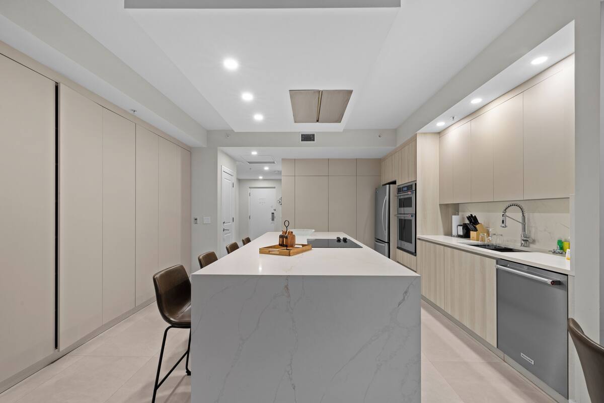 Ett modernt kök med en central köksö, inbyggda vitvaror och en minimalistisk design.