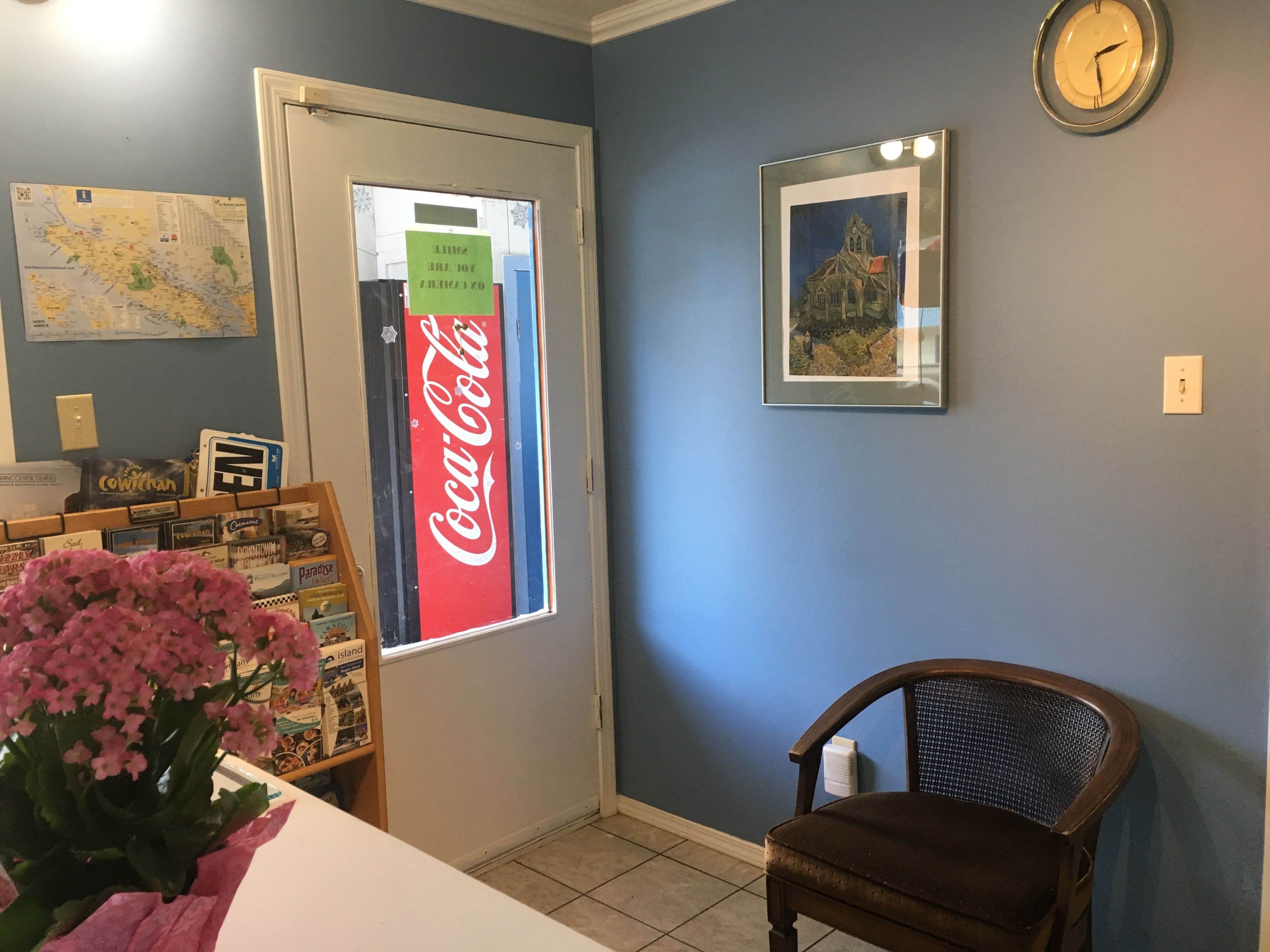 Une pièce avec une carte, une enseigne Coca-Cola, un tableau encadré et une chaise.