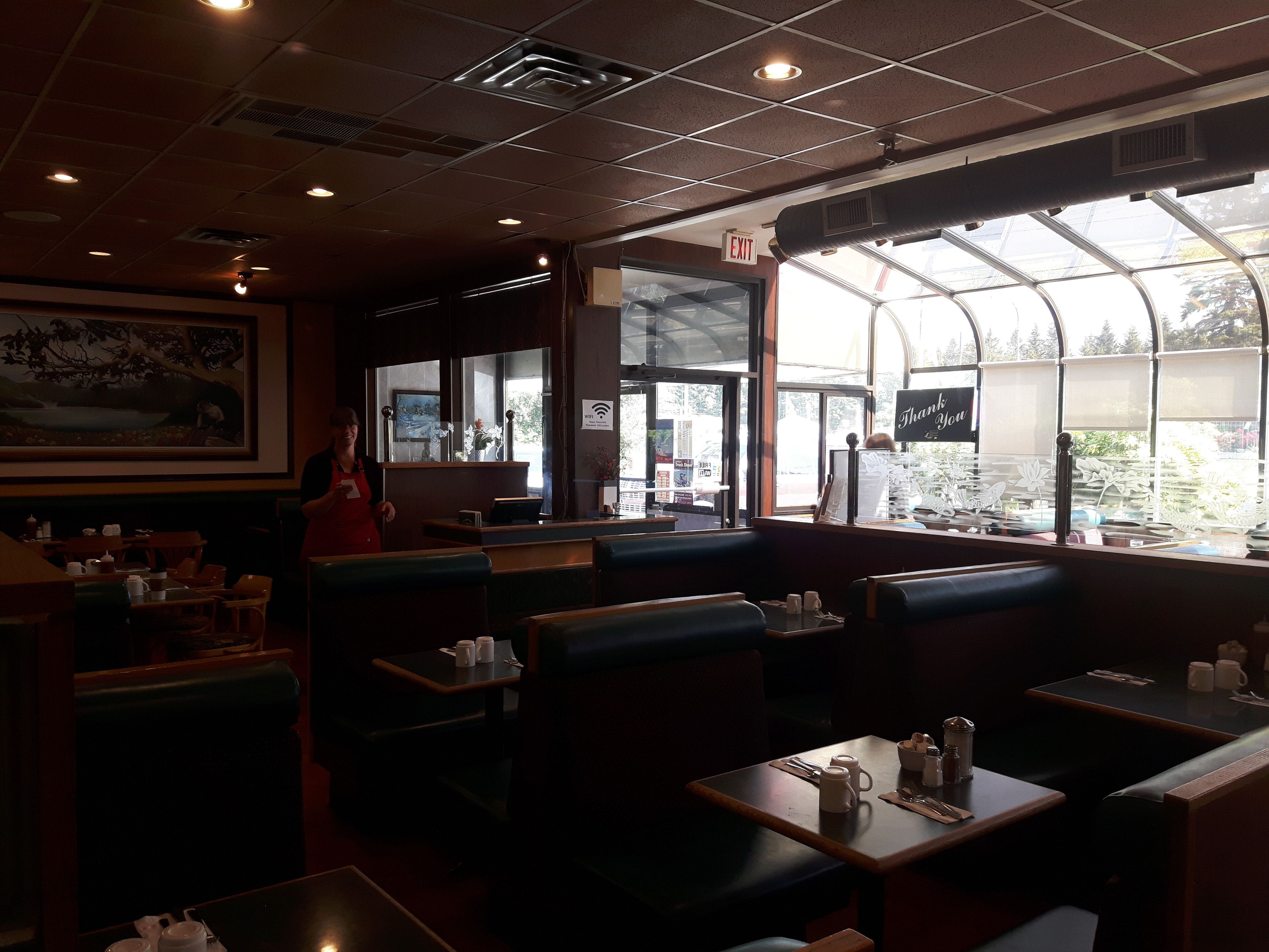 Un interior de restaurante con cabinas, mesas y un ventanal que ofrece vistas al exterior.