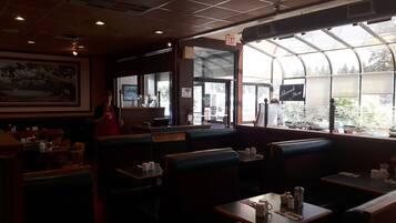 A restaurant interior with booths, tables, and a large window offering a view of the outdoors.