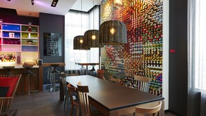 A modern bar area with a long wooden table, multiple bar stools, and hanging wicker lamps. - Hôtel Alt Quartier DIX30 (Brossard)