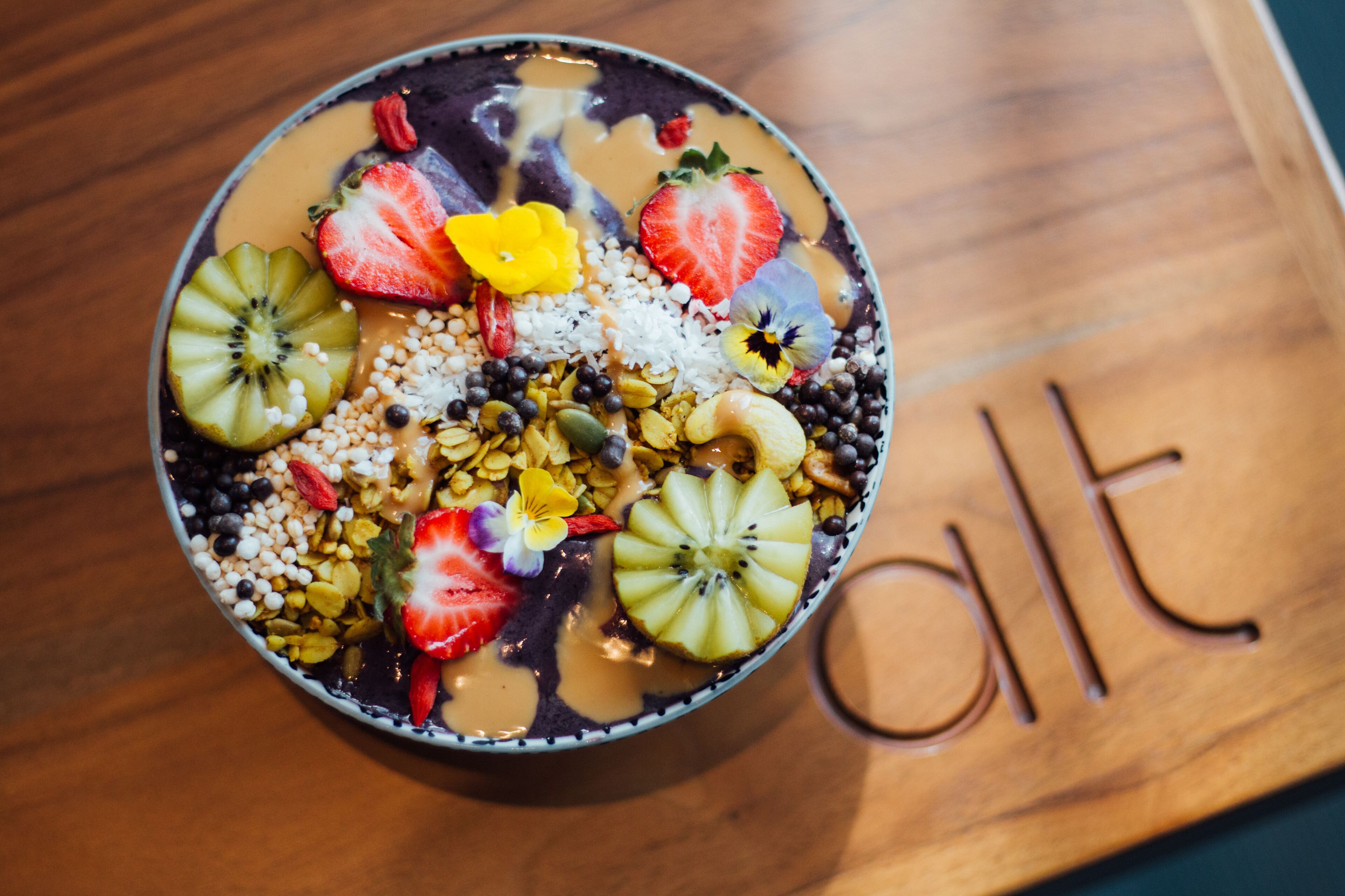 Un tazón de fruta colorida y granola sobre una mesa de madera.