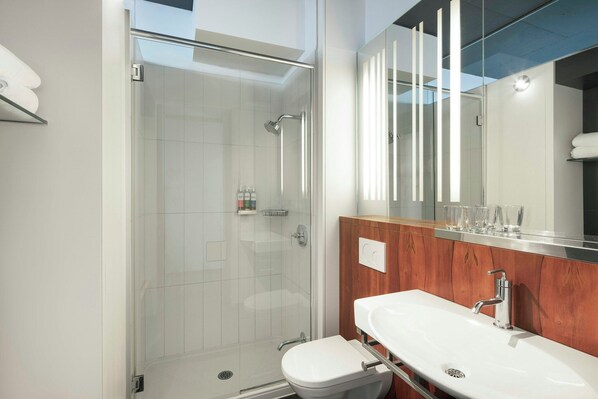 A modern bathroom with a glass-enclosed shower, a wooden vanity, and a large mirror.