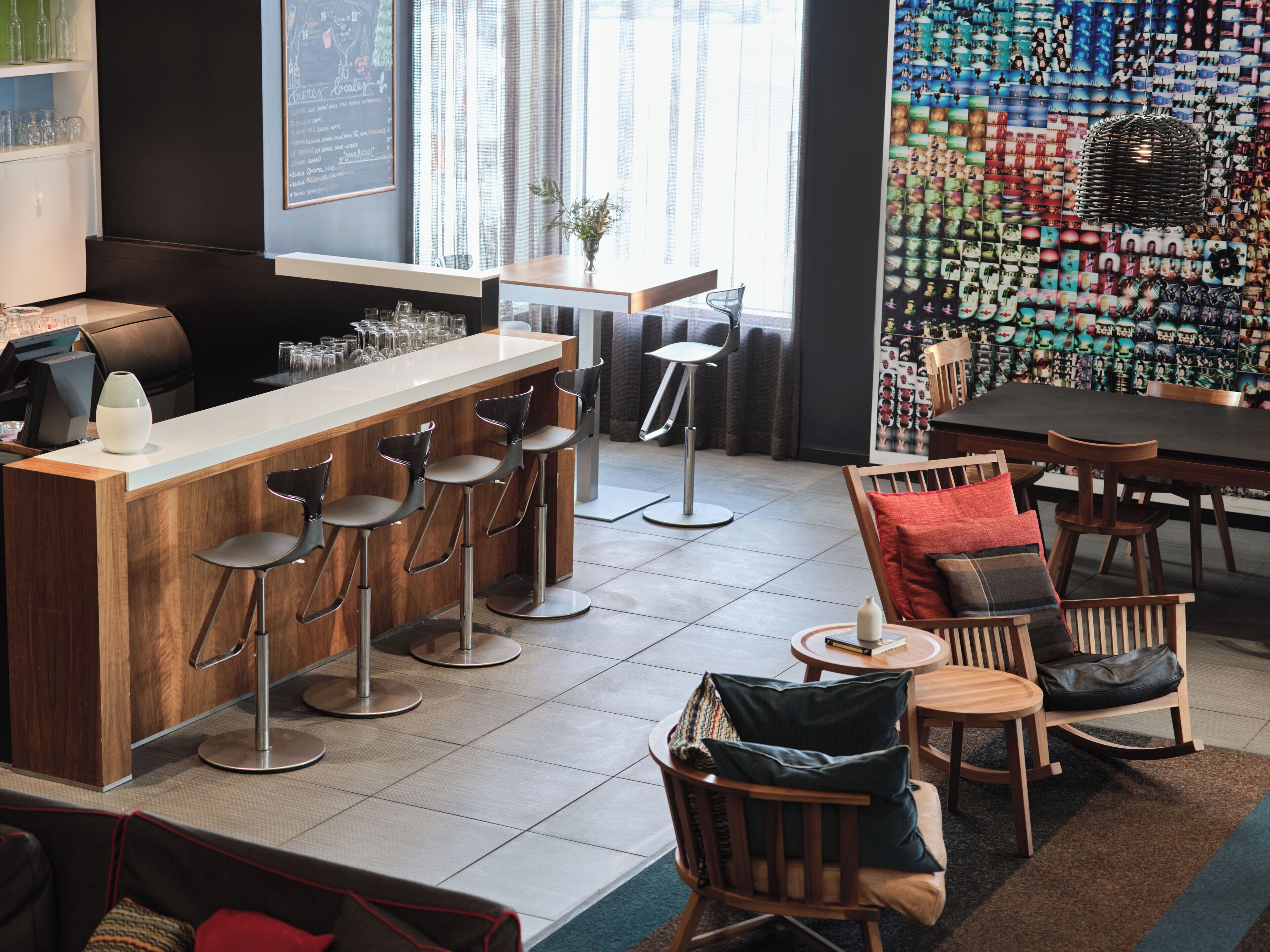 Una zona de bar con taburetes, una barra y una pared de fotografías.