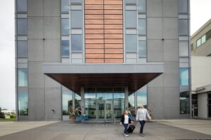 A modern building with a large entrance, glass doors, and a wooden panel accent.
