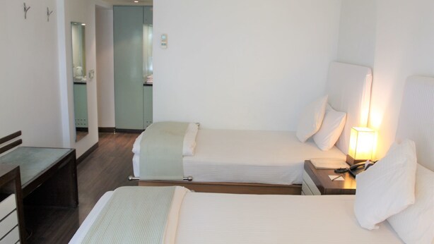 A hotel room with two beds, a desk, and a mirror. - RnB Select The Clover (Gurugram)