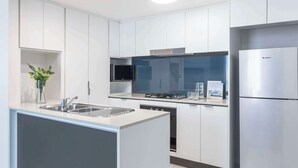 Una cocina moderna con armarios blancos, electrodomésticos de acero inoxidable y una isla central con lavamanos.