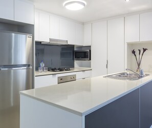 Una cocina moderna con un refrigerador de acero inoxidable, un microondas, una estufa a gas y un lavaplatos.