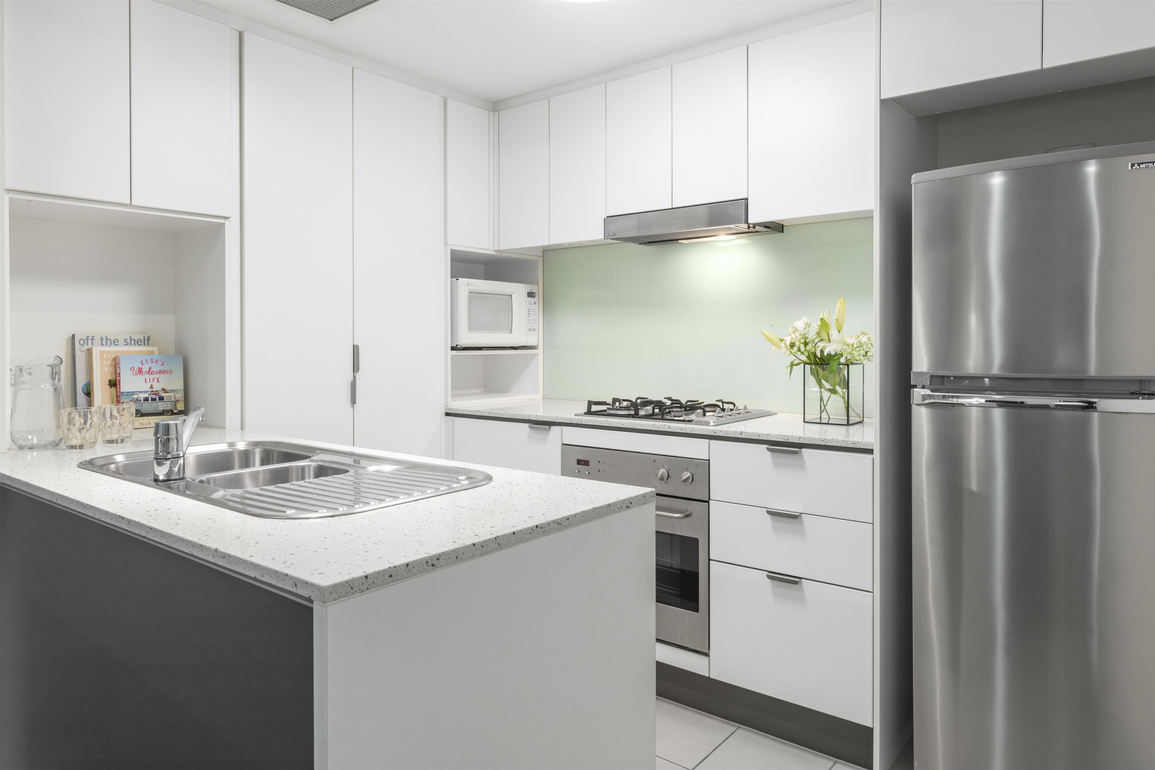 A modern kitchen with white cabinetry, stainless steel appliances, and a built-in microwave.