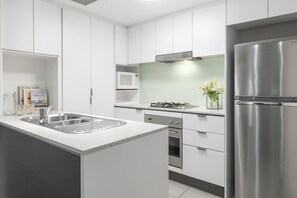 Una cocina moderna con armarios blancos, electrodomésticos de acero inoxidable y un microondas integrado.