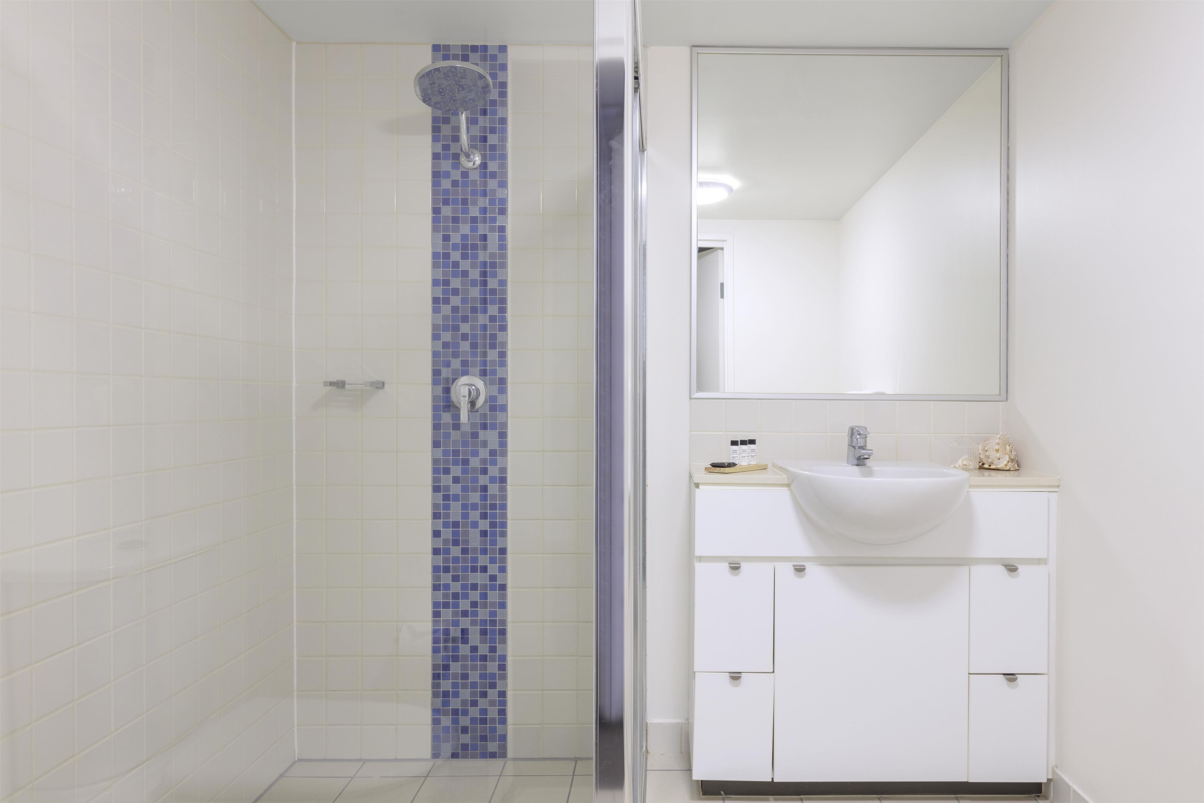 A bathroom with a shower, a sink, and a mirror.