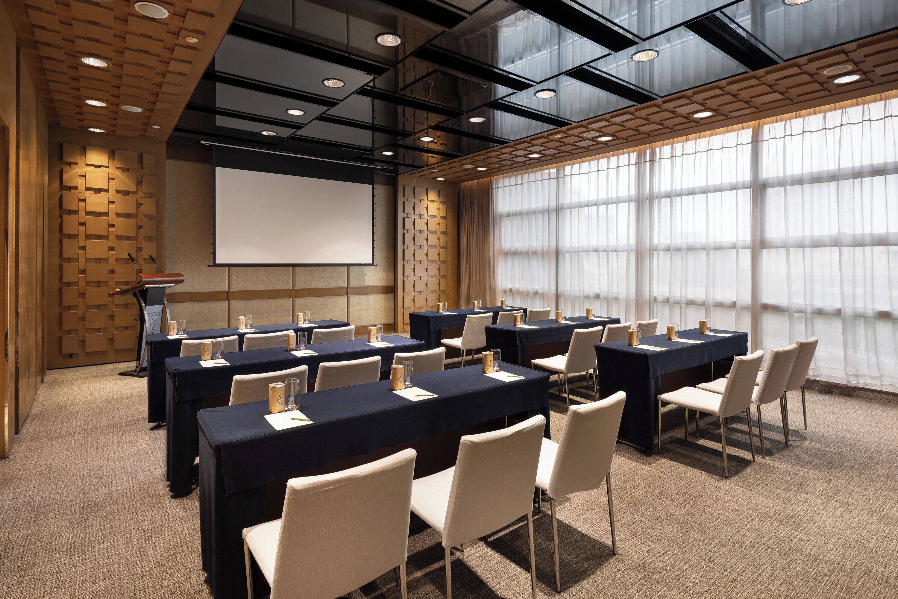A conference room with multiple tables and chairs, a projector screen, and a podium.