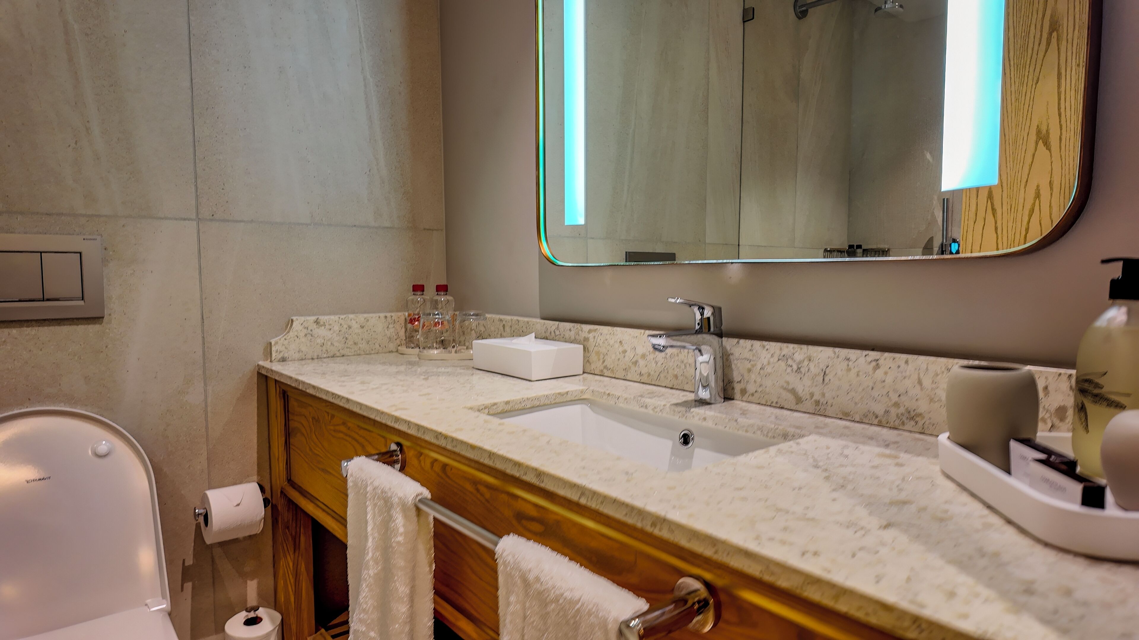 Un baño con encimera de mármol, lavabo, espejo y retrete.