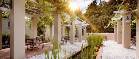 An outdoor patio with pergolas, seating, and a water feature.