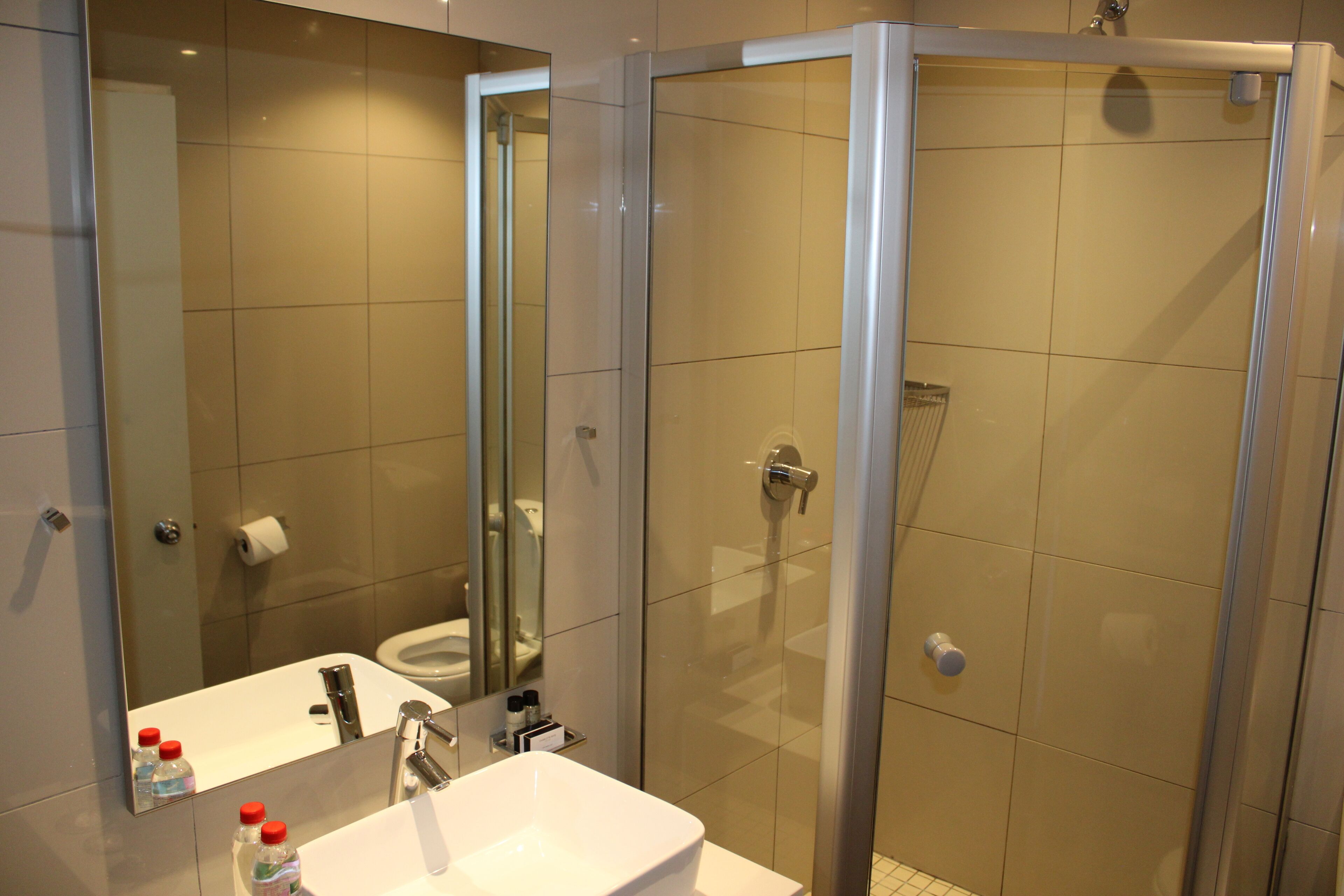A modern bathroom with a glass-enclosed shower, a white sink, and a mirror.