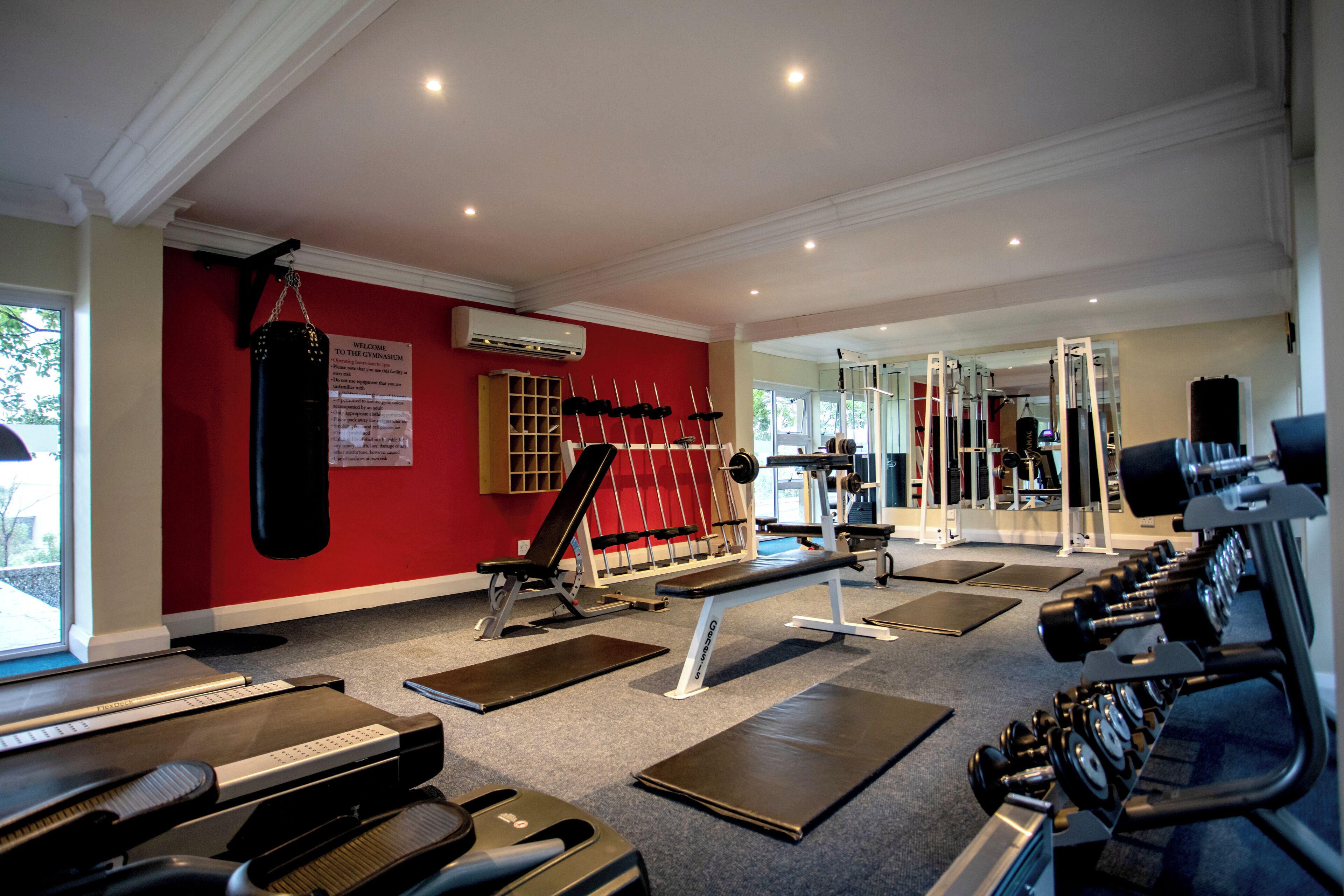 Un gimnasio con cintas de correr, un saco de boxeo y máquinas de pesas.