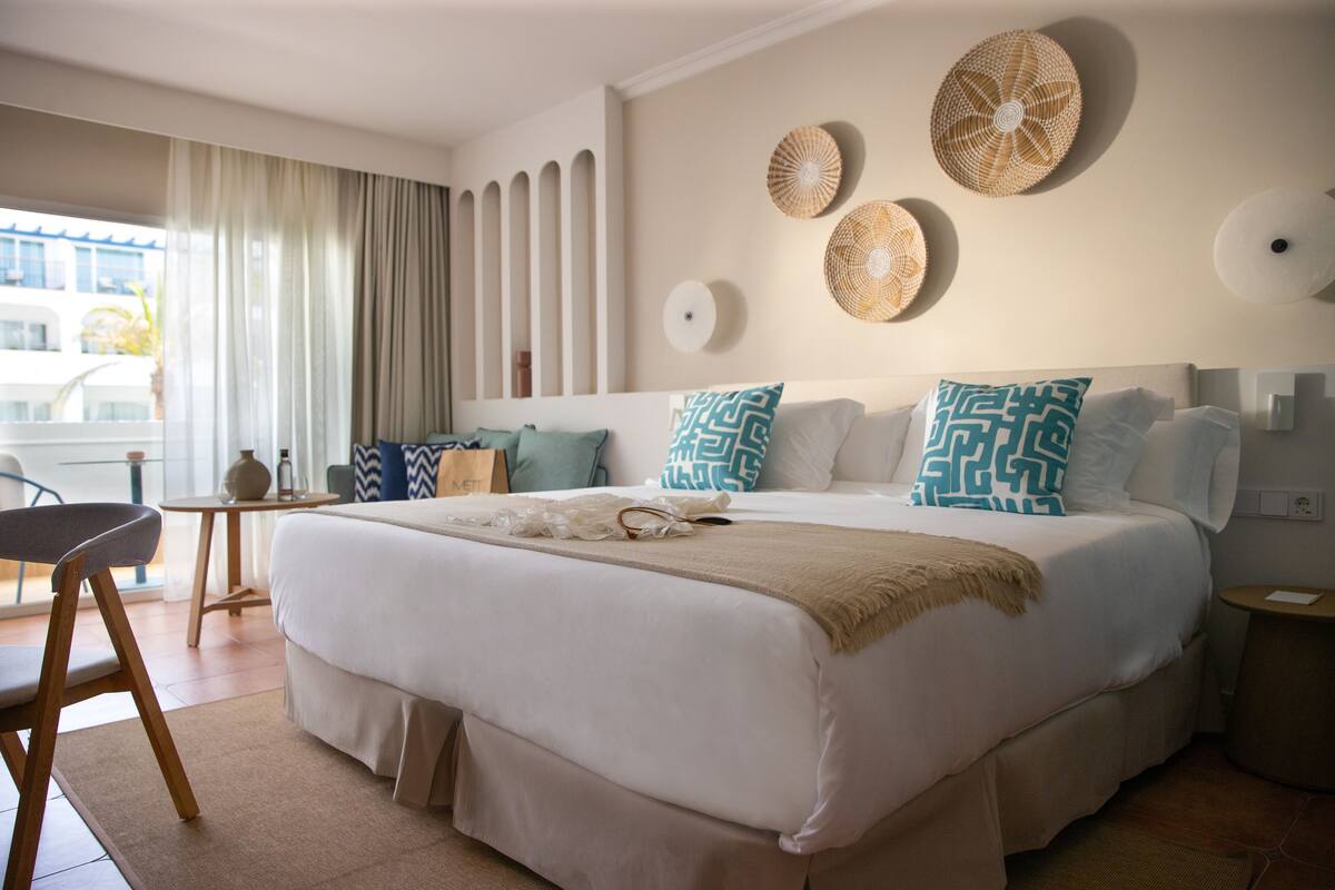 A neatly arranged hotel room with a large bed, a small table, and a chair.
