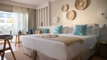 Habitación de hotel ordenada con una cama grande, una mesita y una silla.