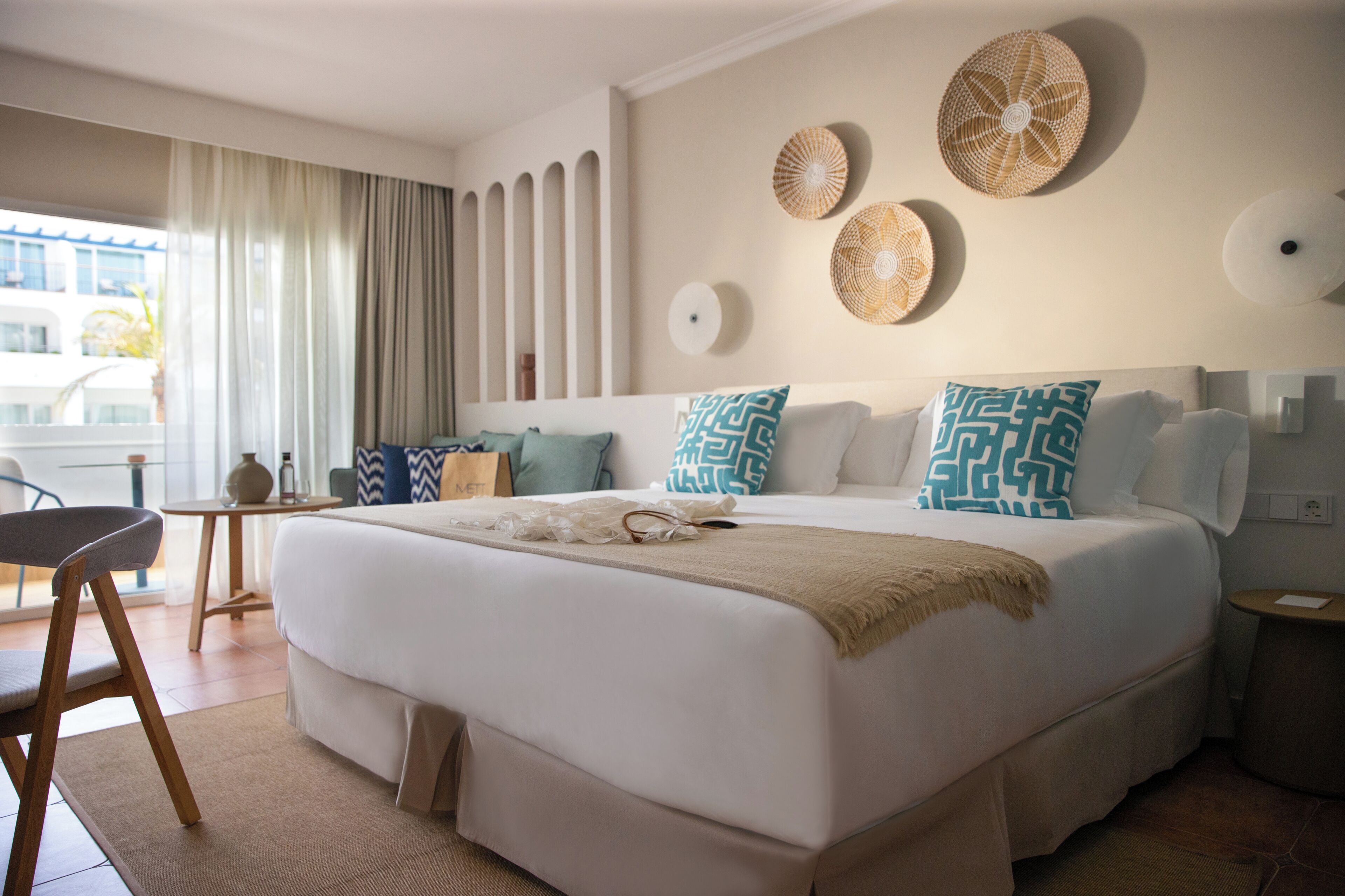 Een moderne hotelkamer met een groot bed, een klein tafeltje, een stoel en uitzicht op het omliggende landschap.