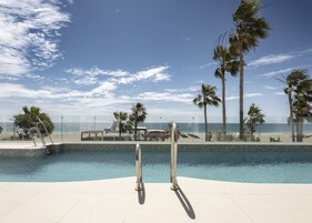 Ein Pool mit Blick auf den Strand und Palmen.