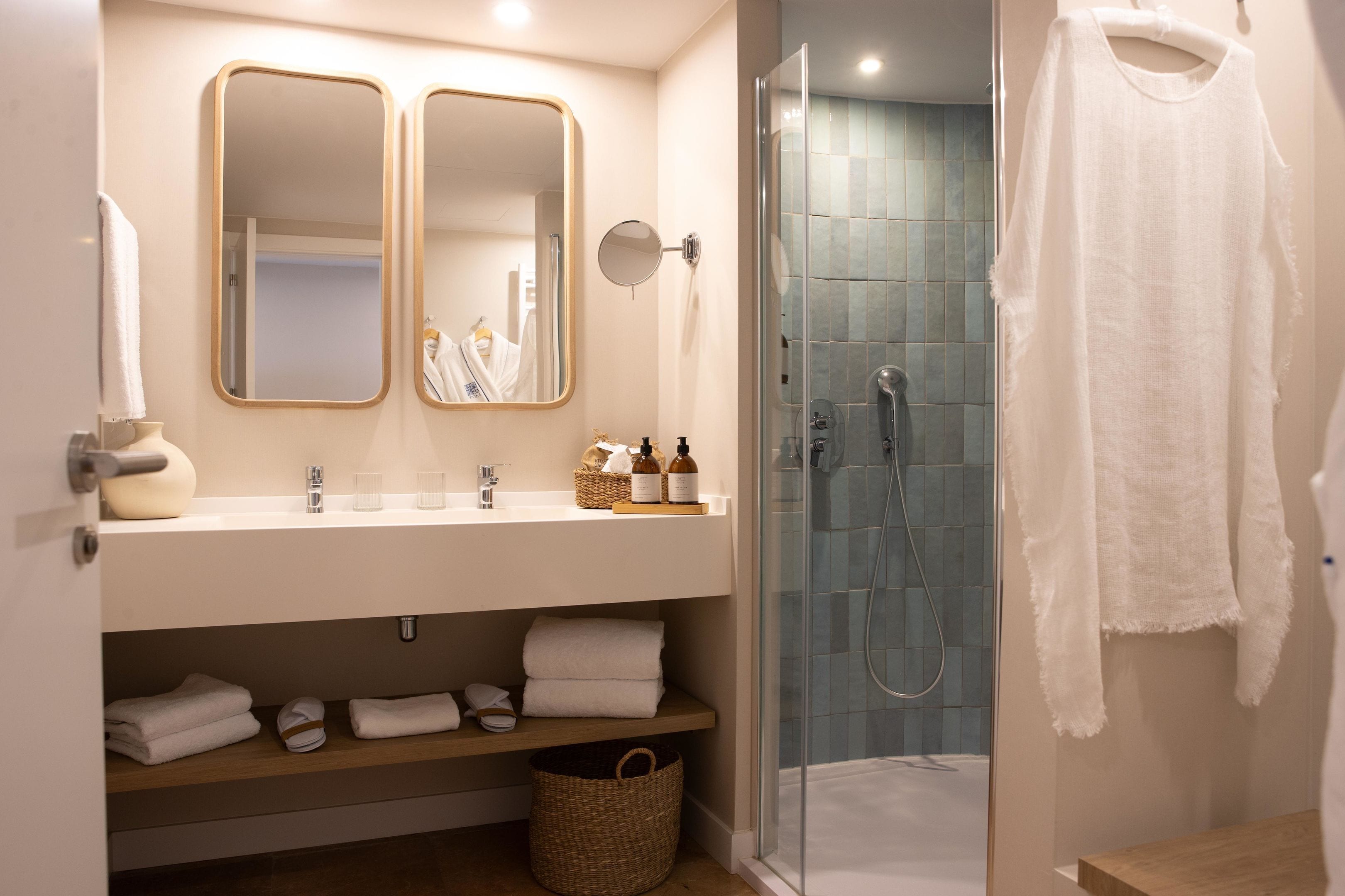 A modern bathroom with a glass-enclosed shower, a vanity with two mirrors, and neatly folded towels.