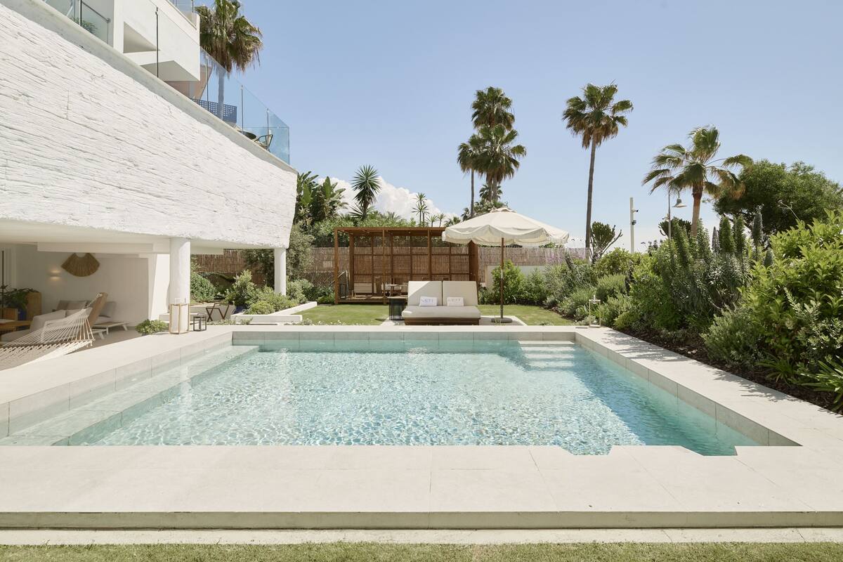 A modern pool area with a clear pool, lounge chairs, and a wooden deck.