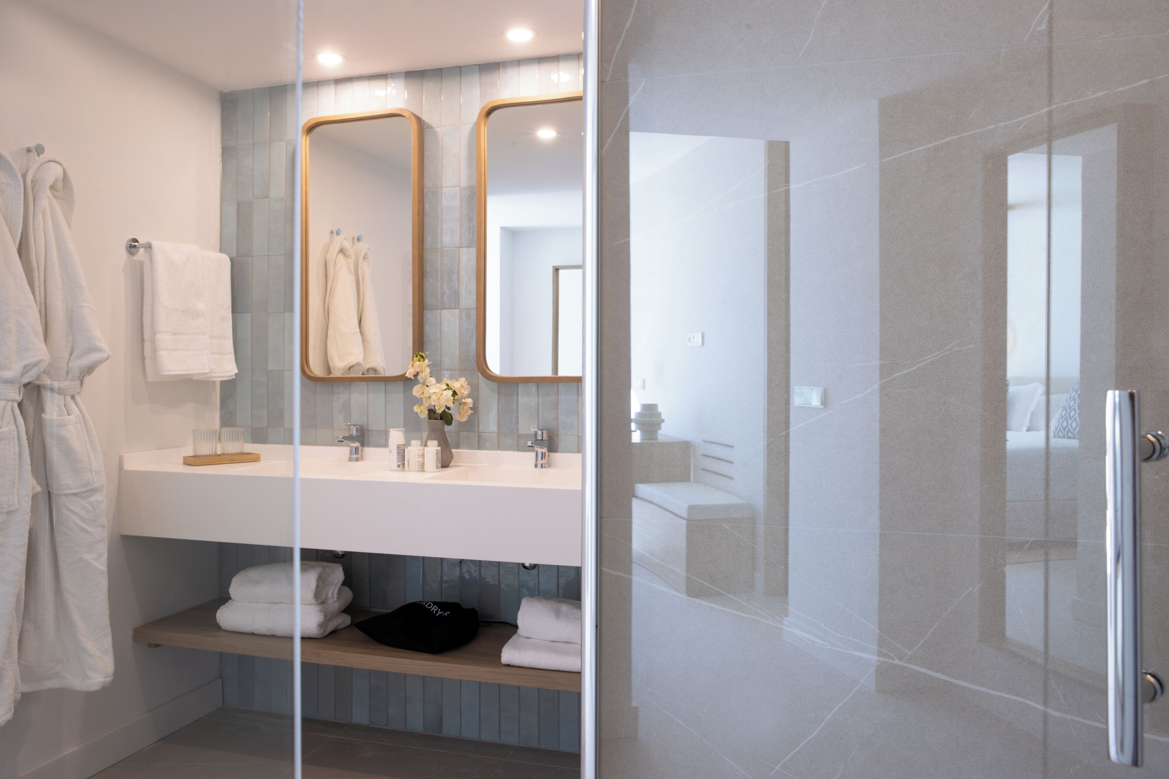 Un baño moderno con cabina de ducha de vidrio, tocador con espejo y perchero.
