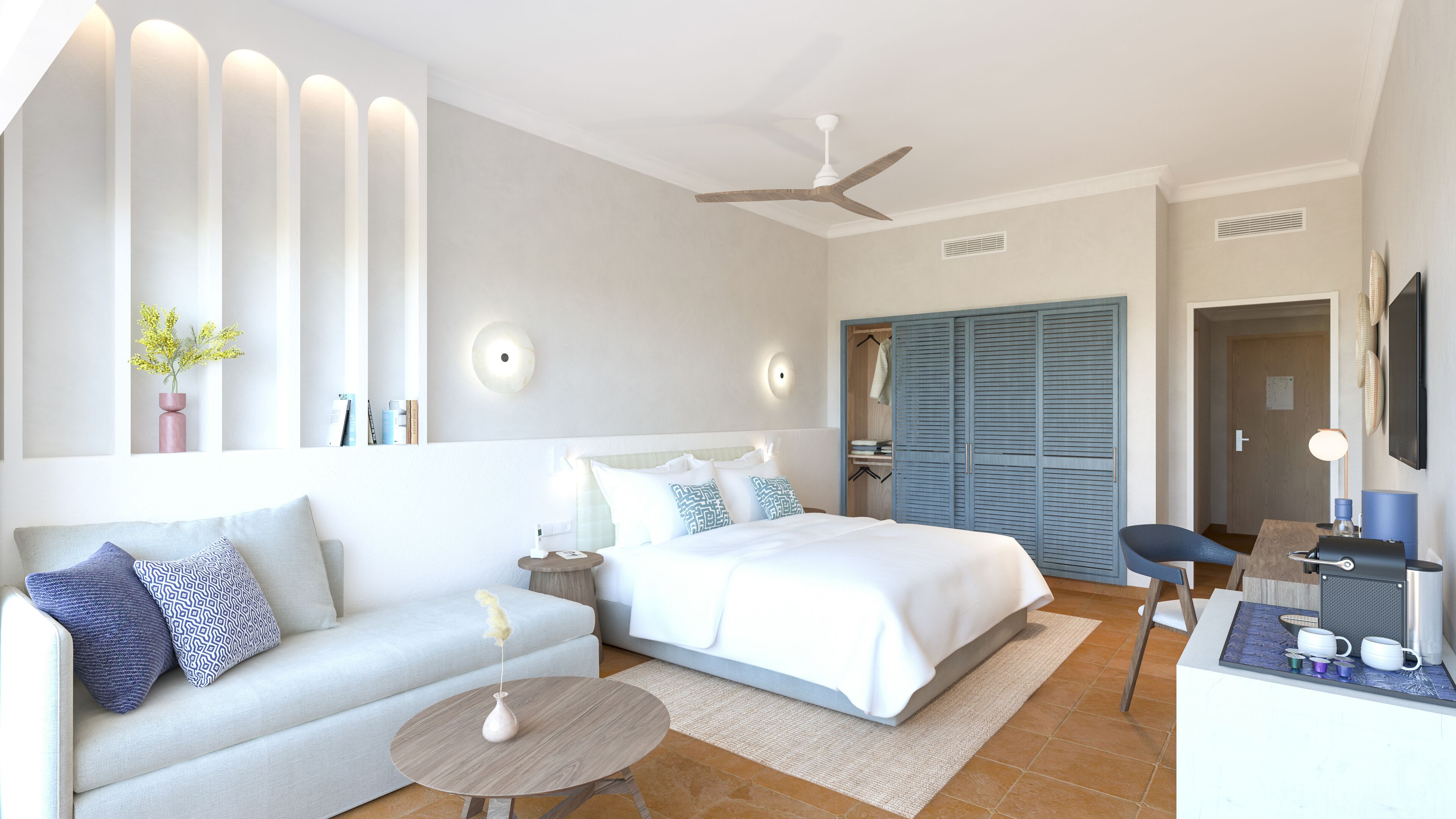 A modern hotel room with a large bed, a sofa, a desk with a chair, and a ceiling fan.