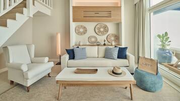 Un salón con escalera, un conjunto de sofás, una mesa de centro y decoración en las paredes.