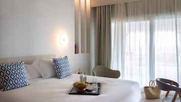Una habitación de hotel con una cama grande, una mesita de noche con una bandeja, un cuenco de fruta y una silla.