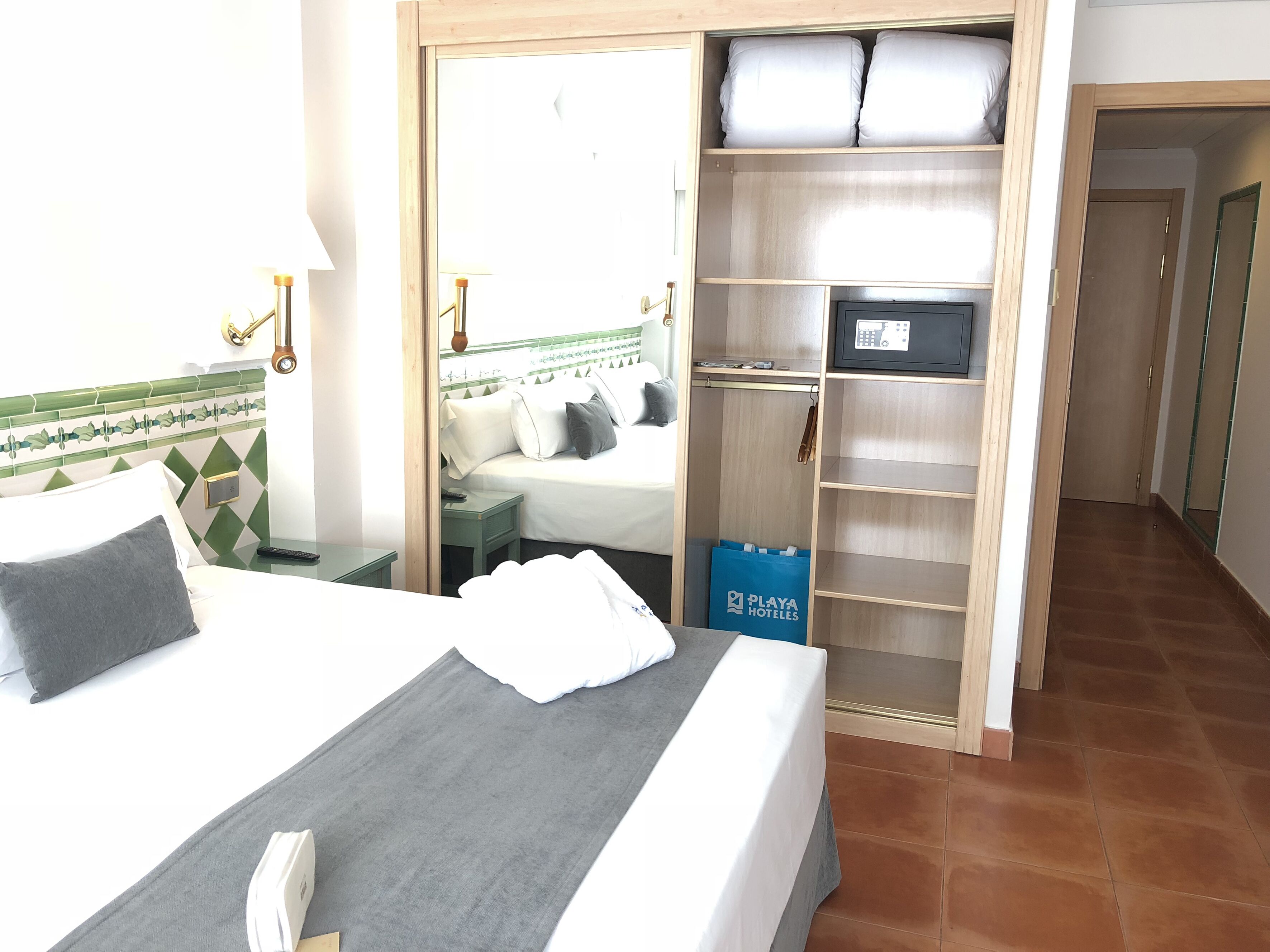 Una habitación de hotel con cama, mesita de noche, armario y puerta al baño.