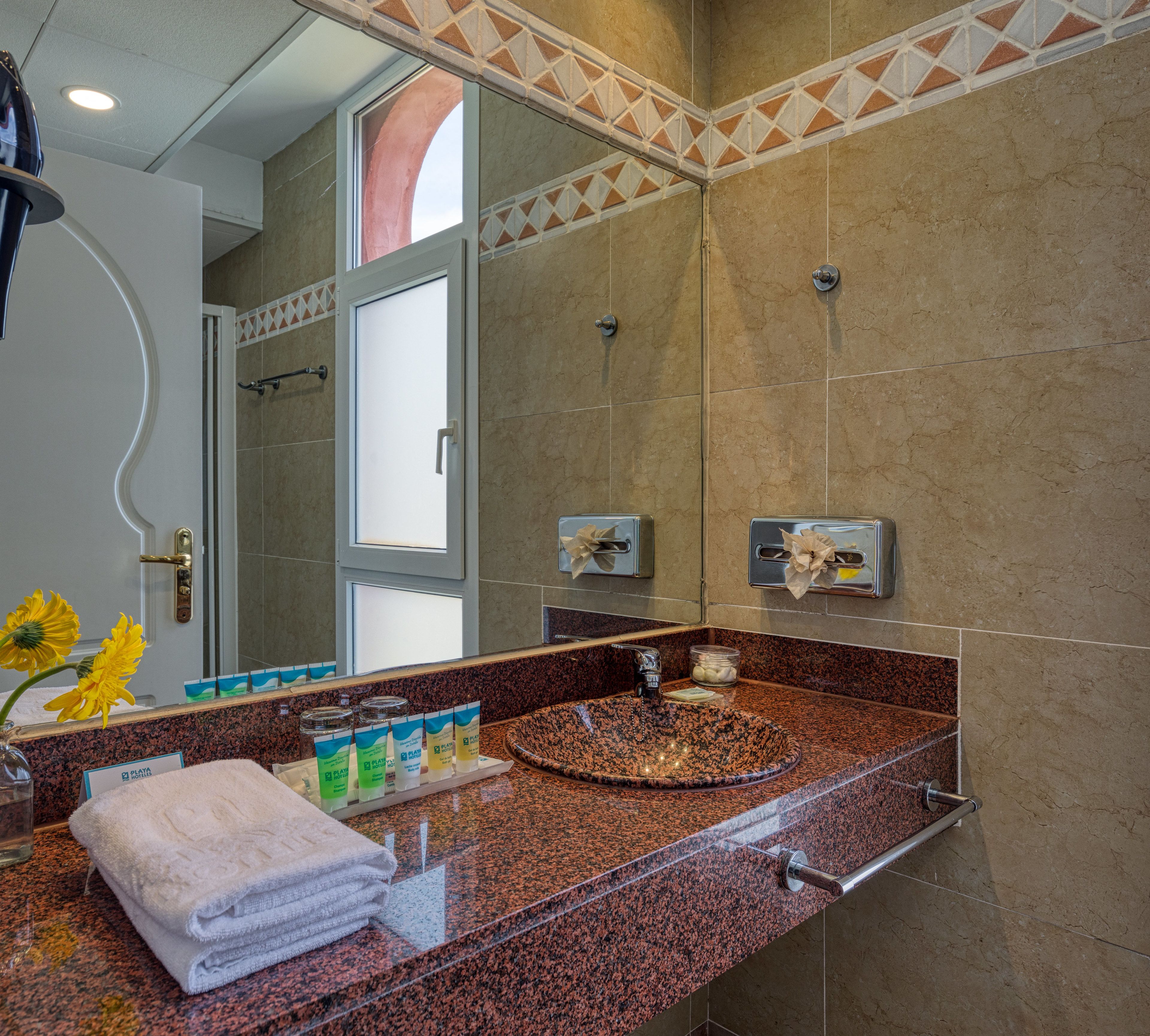 Une salle de bain avec un comptoir en granit, un lavabo, un porte-serviettes et un miroir.