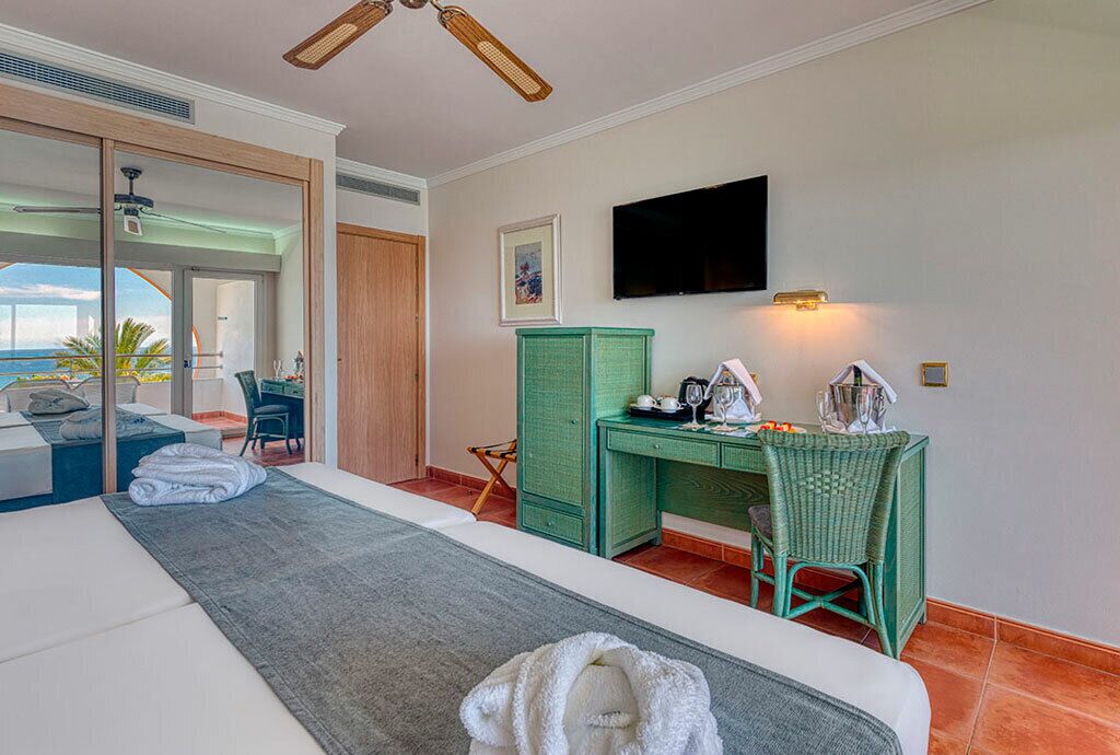 Une chambre d’hôtel équipée d’un lit, d’un bureau, d’une chaise, d’une télévision et offrant une vue sur l’extérieur.