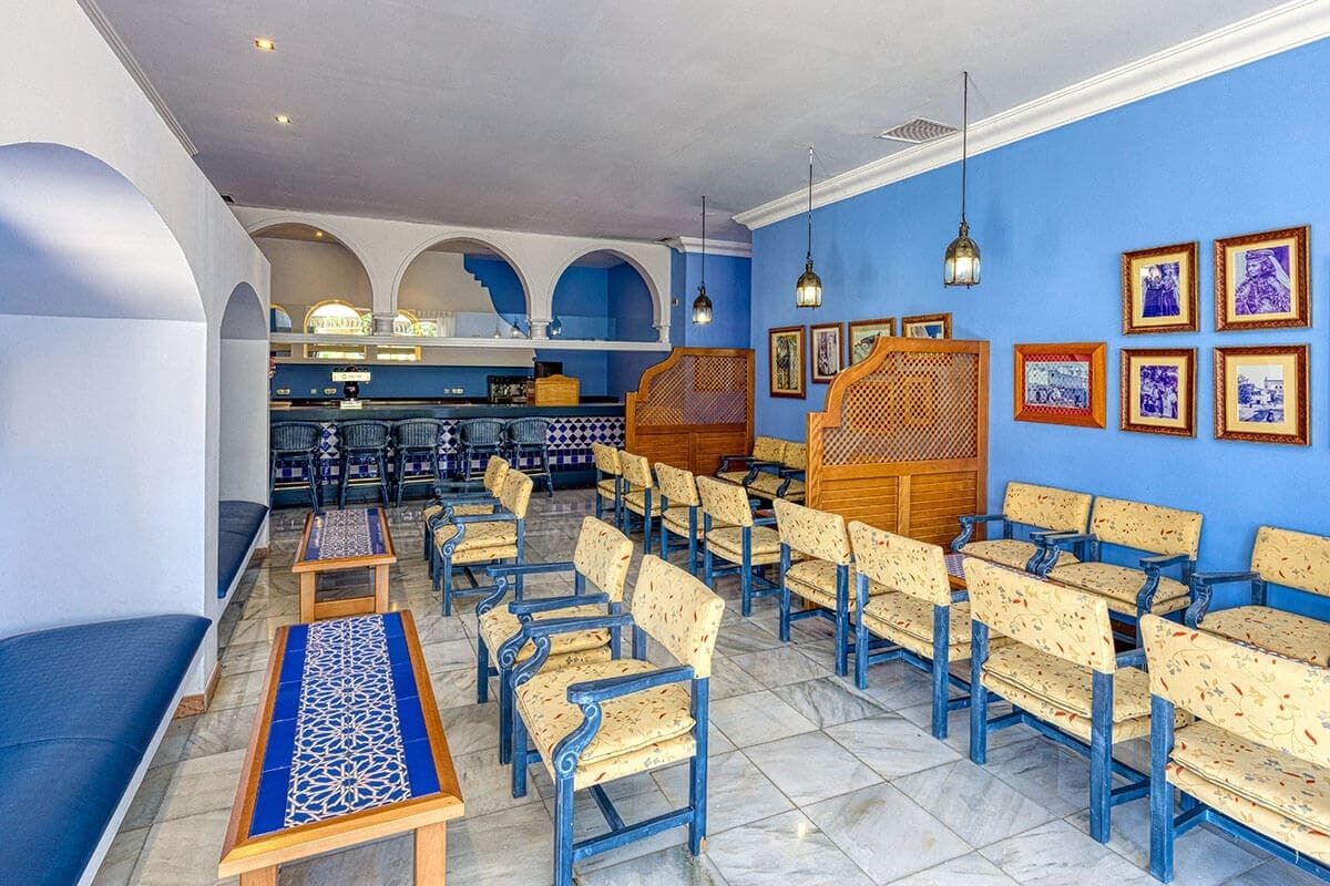 A restaurant with blue walls, wooden furniture, and framed pictures on the walls.