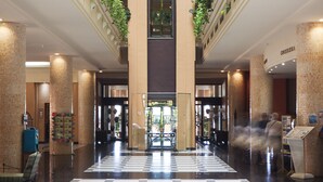 A spacious lobby with a checkered floor, a central elevator, and walls adorned with greenery. - Playacanela Hotel (Ayamonte)
