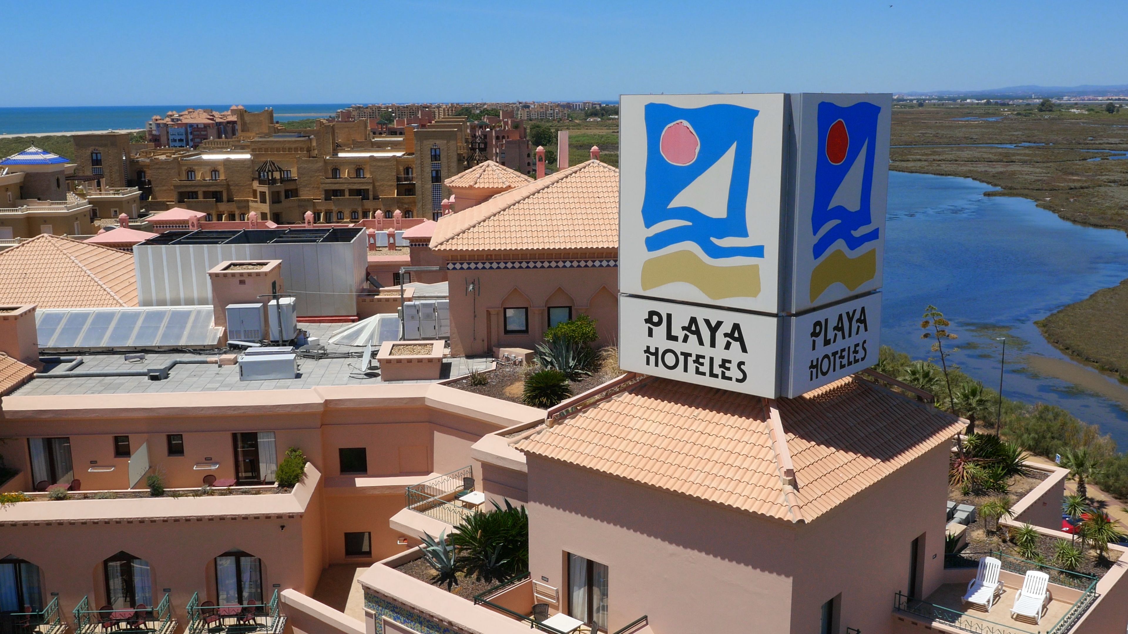Un complexe hôtelier comprenant plusieurs bâtiments, des panneaux solaires sur le toit et une enseigne indiquant « Playa Hoteles ».