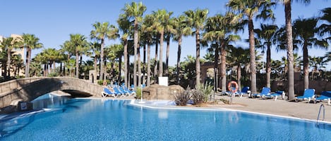 Una piscina techada, una piscina al aire libre, sombrillas