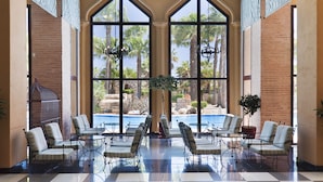 A poolside lounge with large windows, lounge chairs, and a central table. - Playacanela Hotel (Ayamonte)
