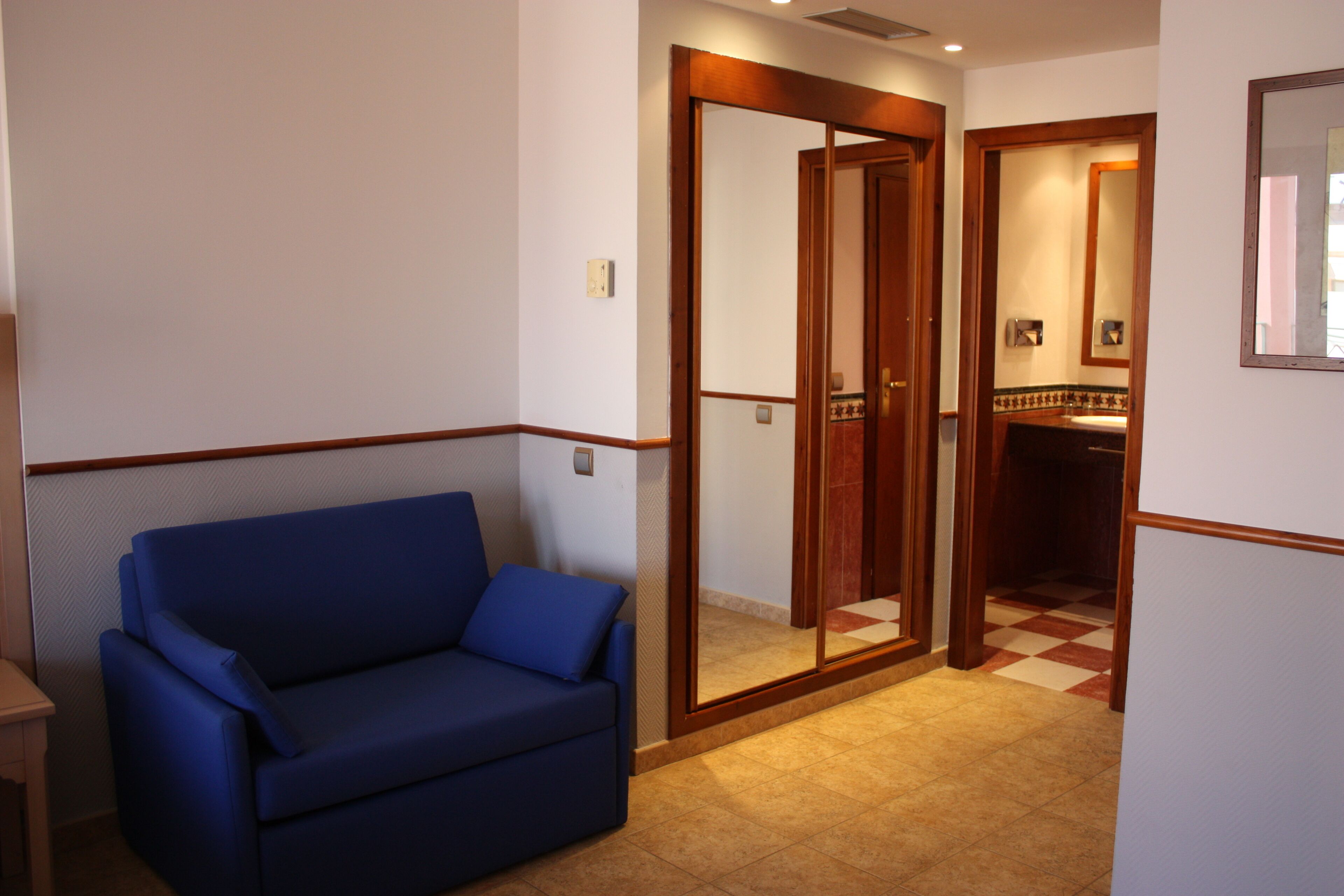 A room with a blue sofa, a wooden door, and a tiled floor.