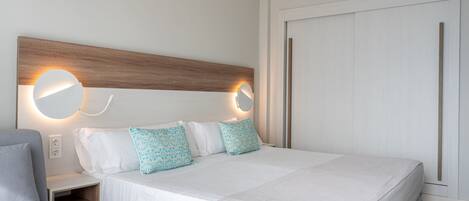 Una habitación de hotel moderna con una cama grande, dos mesitas de noche y un armario.