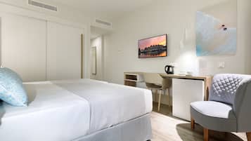 Una habitación de hotel con una cama, un escritorio, una silla y un cuadro en la pared.