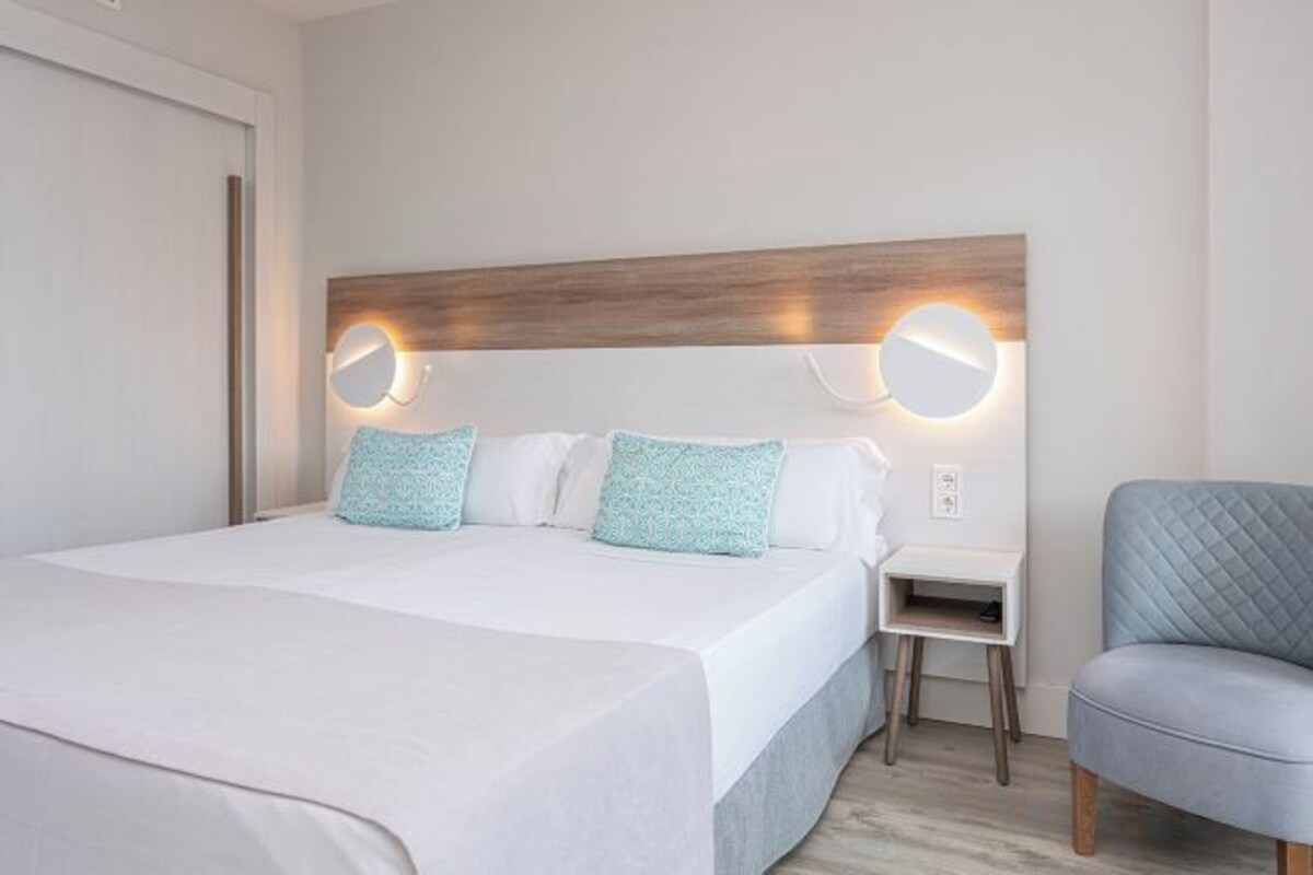 Une chambre d’hôtel avec un grand lit, des tables de chevet et une chaise.