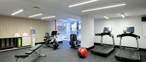 A gym with treadmills, a bench, and exercise balls.
