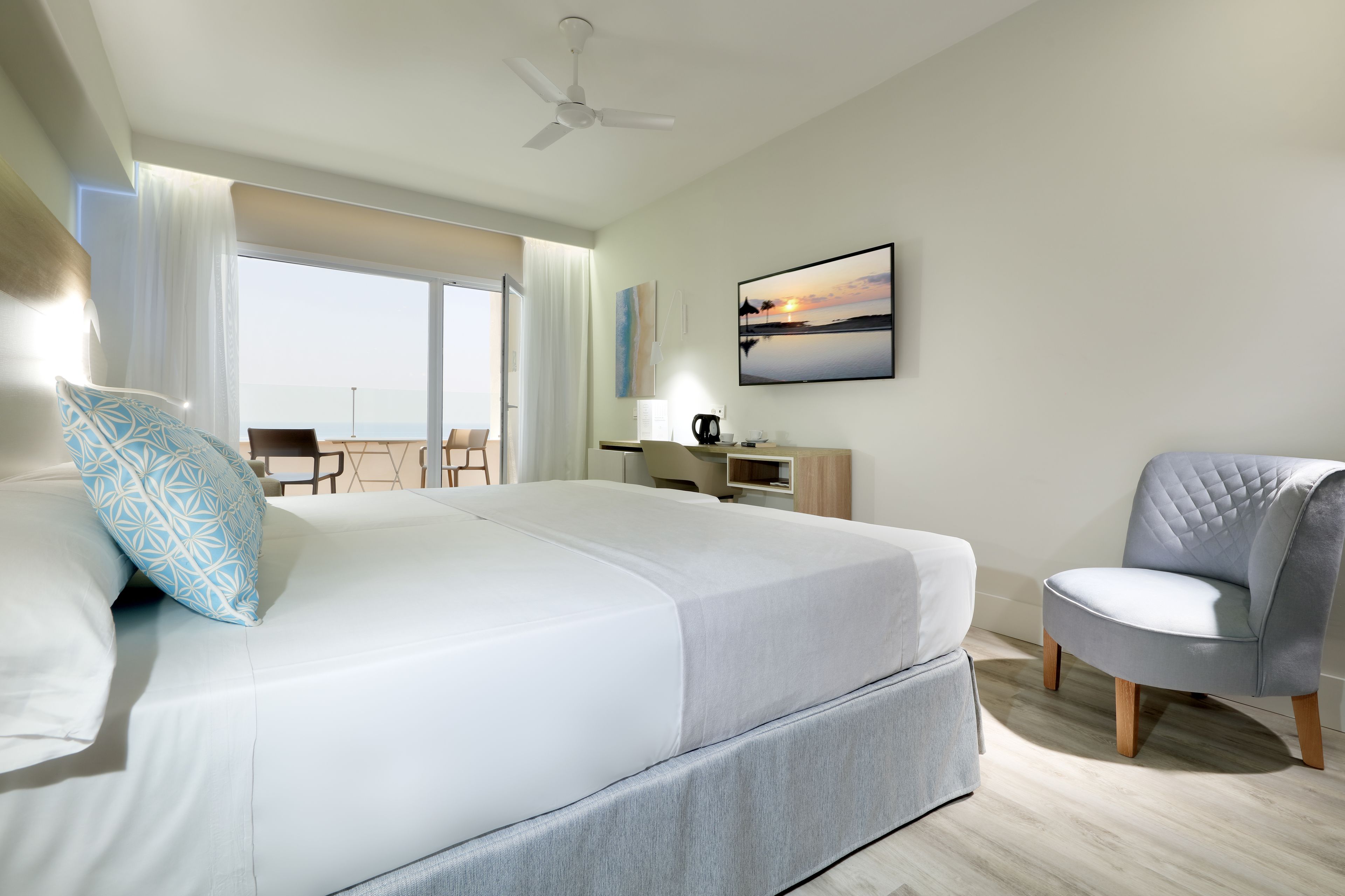 Ein Hotelzimmer mit Bett, Sessel, Schreibtisch, Fernseher und Meerblick.