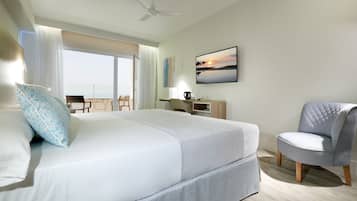 Habitació d'hotel amb llit, una cadira, escriptori, televisió i vista al mar.