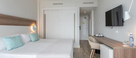 A hotel room with a bed, a desk, a TV, and a ceiling fan.