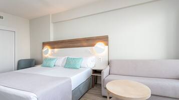 Camera d'albergo con un letto grande, un divano, un tavolino e un comodino con una lampada.