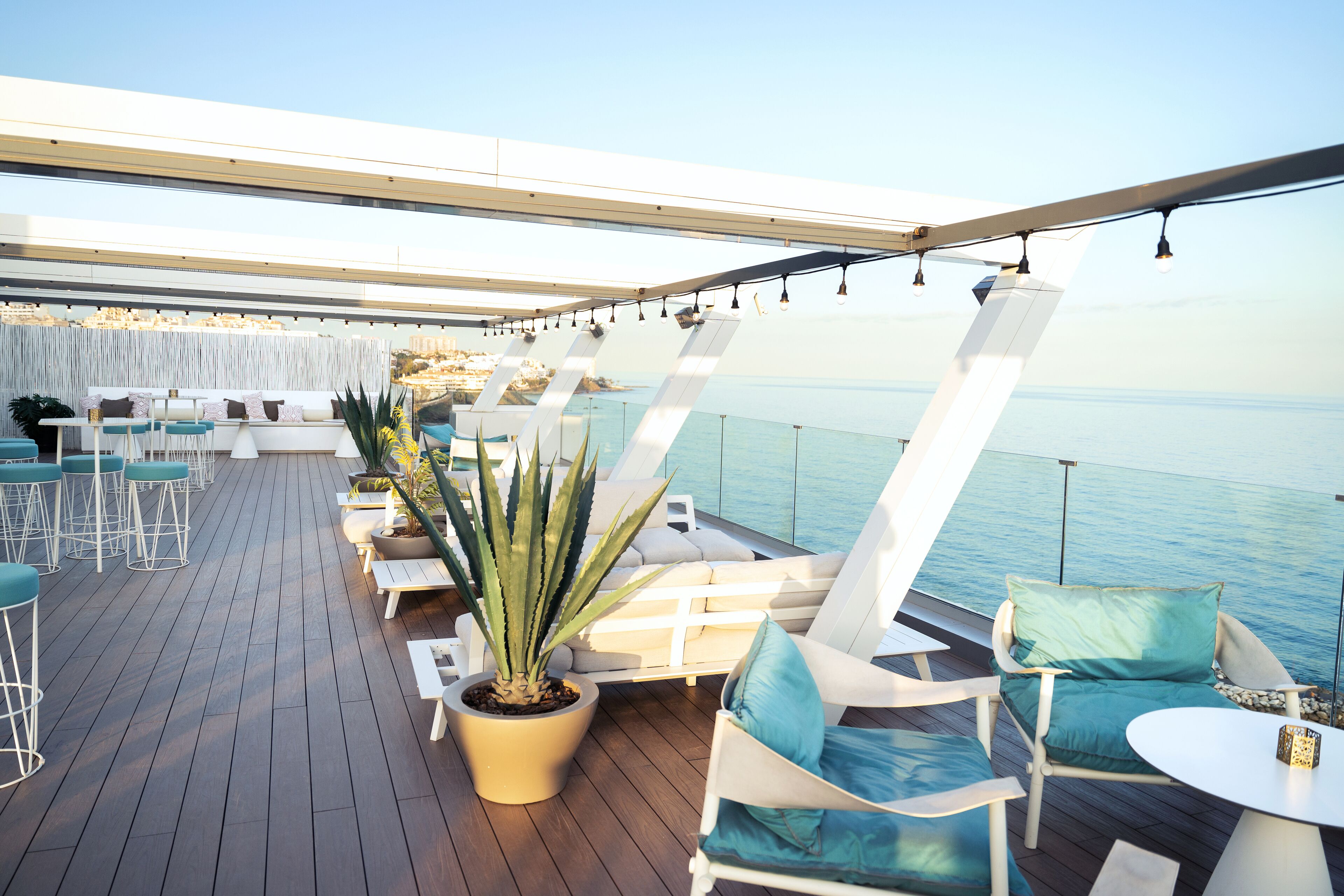 Una terraza con asientos, una planta en maceta y vistas al mar.