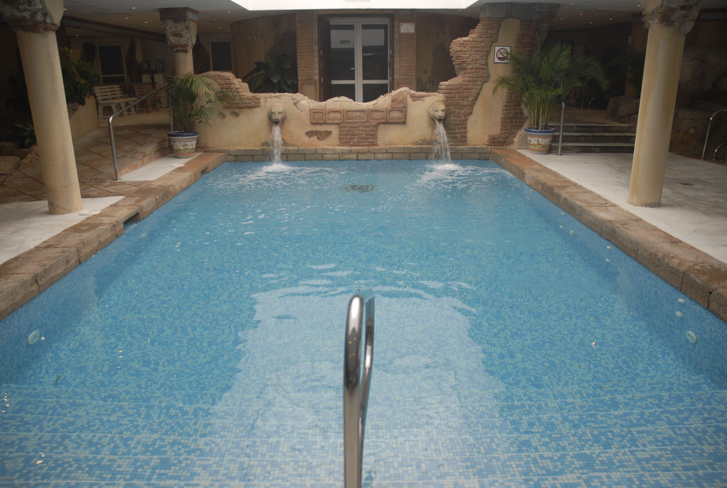 Una piscina con un elemento acuático central y una escalera de metal.