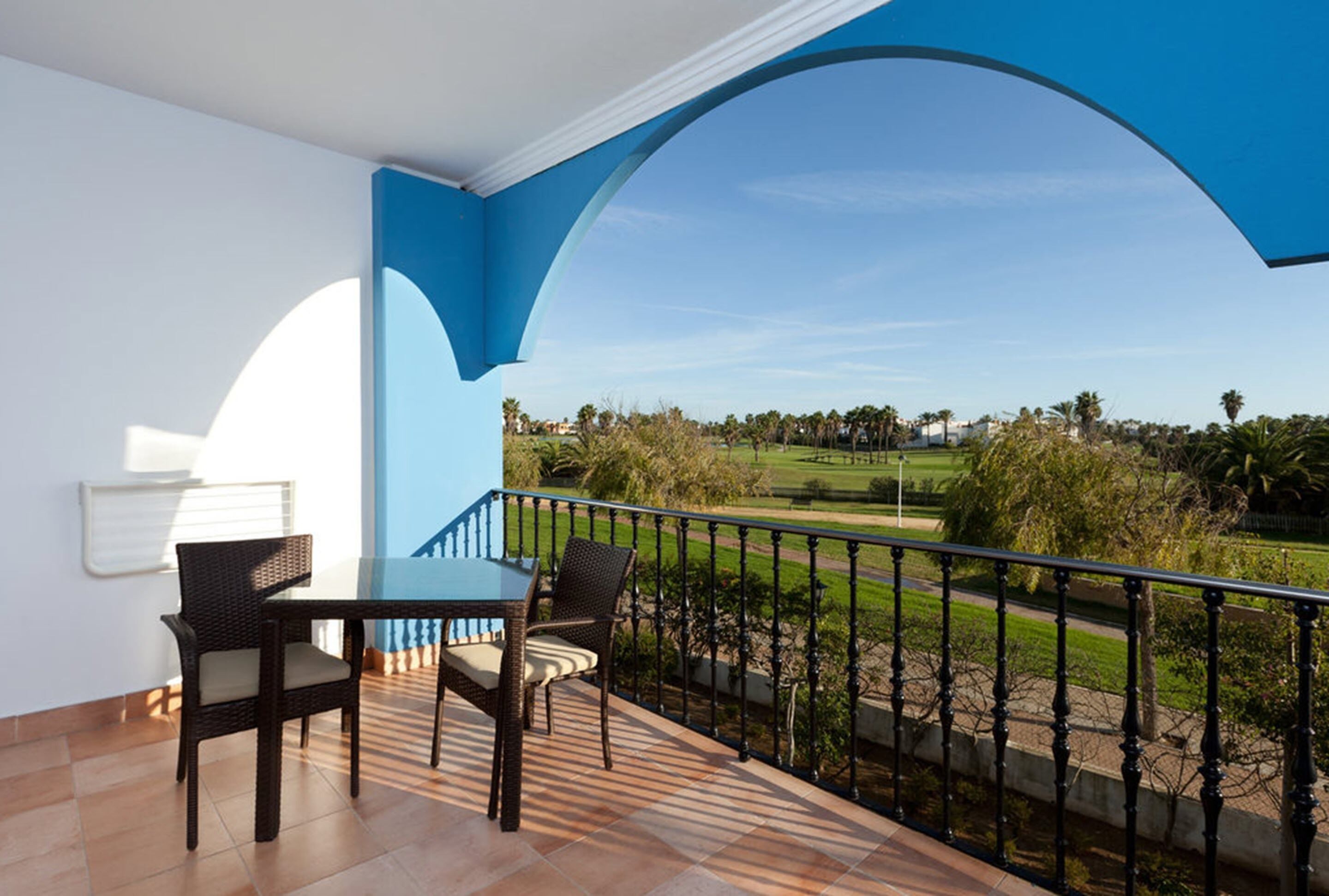Un balcón con una mesa y sillas, con vistas a un campo de golf.